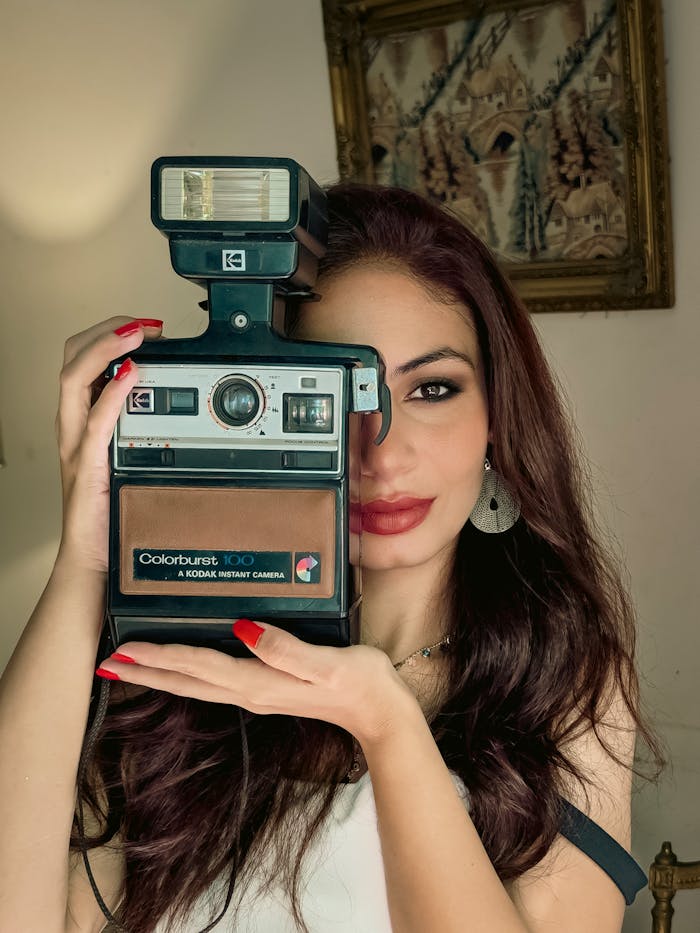 our-story A woman holding a vintage Kodak instant camera, evoking nostalgia.