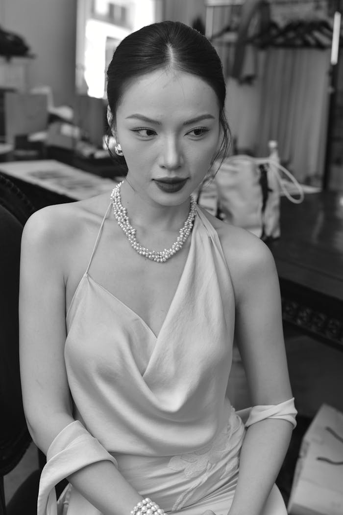 Black and white portrait of a young woman in elegant attire wearing pearls.